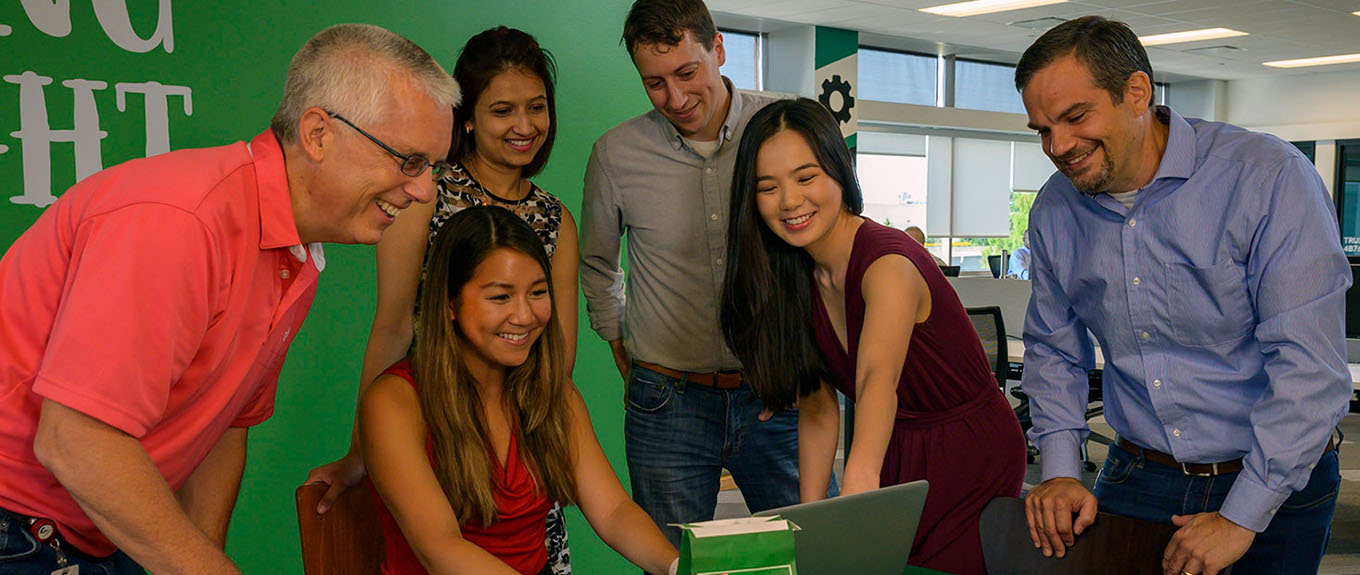 3 multicultural Mondelez staff sitting around a laptop smiling and talking.