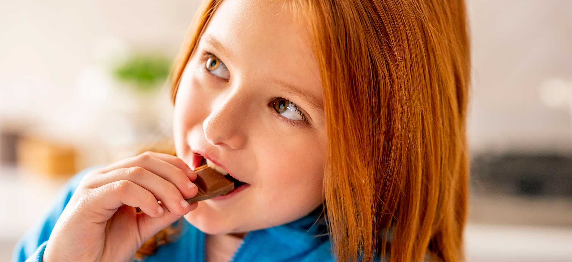 Little girl smiling while she eats a chocolate snack.