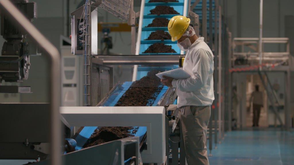 factory worker standing next to conveyor belt