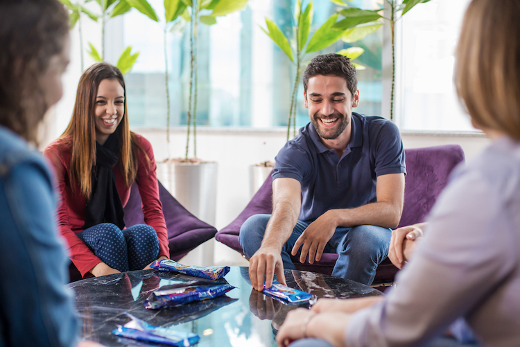 People around a glass table, discussing chocolate, laughing