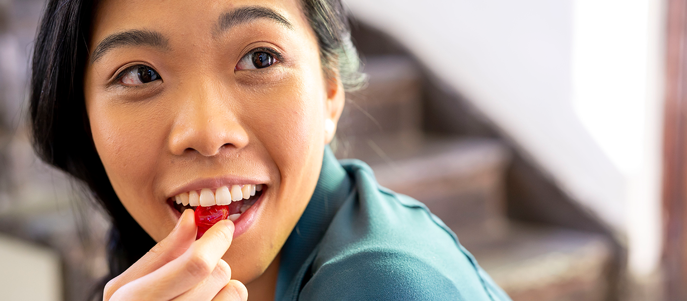Asian woman eating a halls candy and smiling.