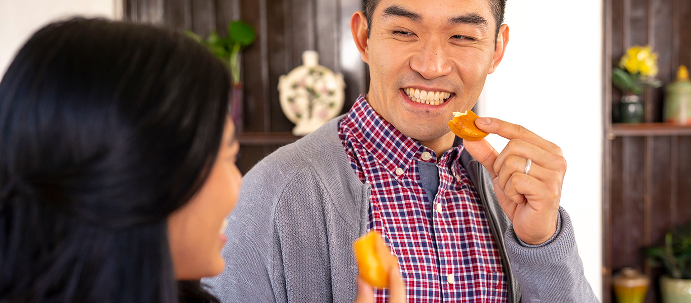 Vietnamese couple smiling and eating a Kinh Do snack.