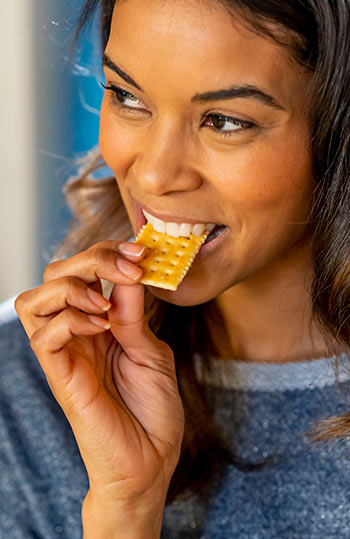 Woman smiling while eating cracker.